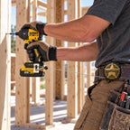 Worker driving a screw with the drill tethered to the Drillslinger on his belt